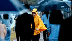 Girl in yellow raincoat running in rain