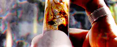 Hand holding a smoking glass pipe