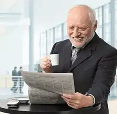 Old man laughing while reading newspaper