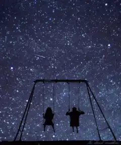 Two silhouettes on swings under starry sky