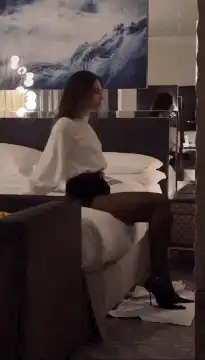 Woman in white blouse and black tights on bed