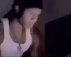 Man in white tank top and cap looking at screen