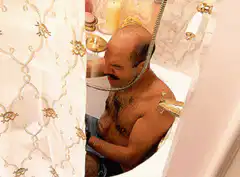 Man in bathtub with shower hose around head
