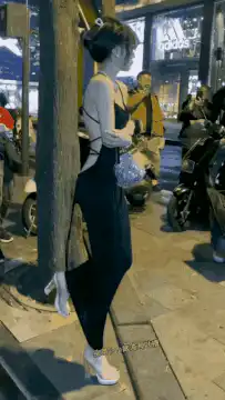 woman posing by tree on street