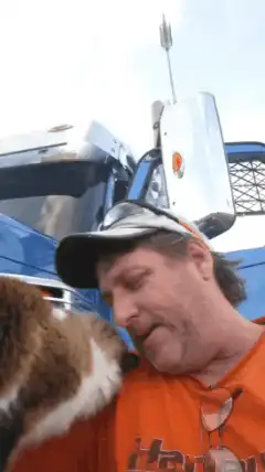 Cat licks man's face in front of truck