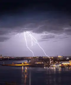 Lightning strikes over city waterfront at night