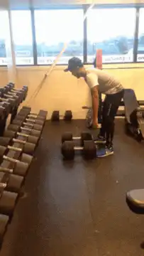 man lifts heavy dumbbell in gym