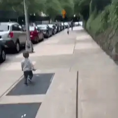two toddlers run and hug on sidewalk