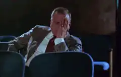 Man in suit facepalms in theater