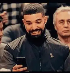 Drake looking at phone and smiling