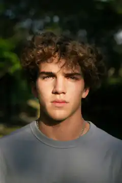 Young man with curly hair looking at camera