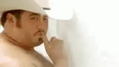 shirtless man in cowboy hat shushing