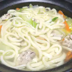Bowl of udon noodle soup with meat and vegetables