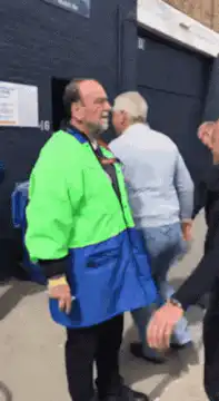 Man in green and blue jacket greeting people