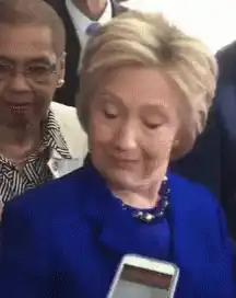 Hillary Clinton looks at phone then smiles