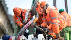 Construction workers securing a large hook