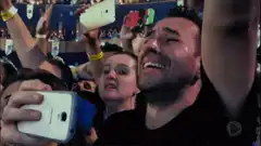 Man laughing while taking selfie in crowd