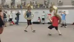 two boys play fight with sousaphones