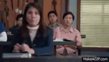 Woman in class looks bored, man behind yawns