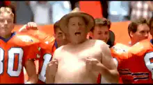 Shirtless man in hat cheering with football players