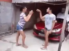 Two men play fighting in front of a red car