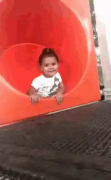 Baby slides down red tube slide