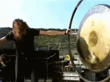 man hits large gong with mallet