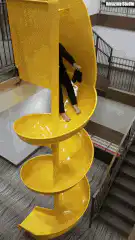 Woman slides down yellow spiral slide