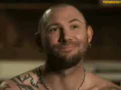 Tattooed man smiles showing missing teeth