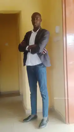 Man in blazer and jeans standing with arms crossed
