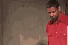 Denzel Washington in red shirt looking down