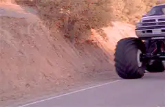 Red Dodge monster truck driving on road