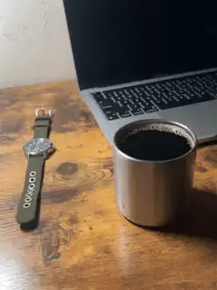 Coffee cup and laptop on wooden desk