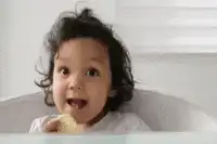 Baby eating and giving thumbs up