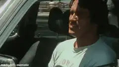 Arnold Schwarzenegger flexing muscles in car