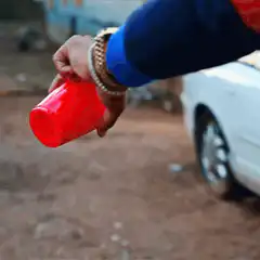 Hand pouring beer from red cup
