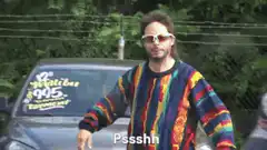 Man in rainbow sweater shushing