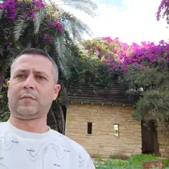 Man in front of stone house with purple flowers
