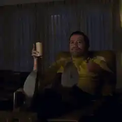 Man in yellow shirt pointing with coffee