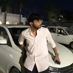 man in pink shirt by car at night