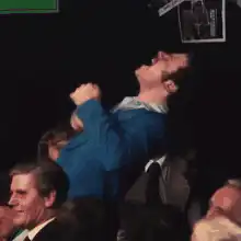 Man in blue shirt throws head back laughing