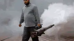 man walking with smoking minigun