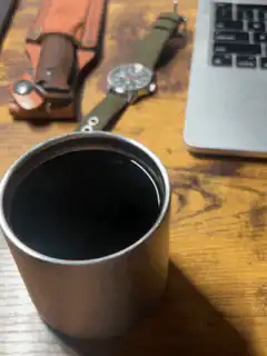 dark liquid in metal cup on wooden desk