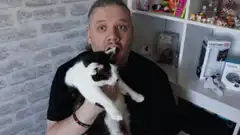 Man holding cat with tongue out