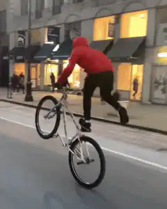 Biker doing wheelie on city street