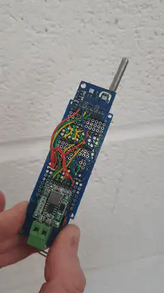 Hand holding a blue circuit board with antenna