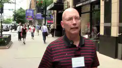 Bald man in striped shirt talking on street