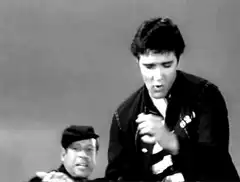 Elvis Presley singing with a man in a cap