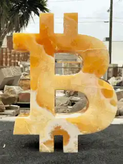 Rotating orange onyx bitcoin sculpture