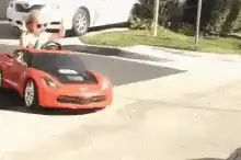 Toddler in toy car with arms up